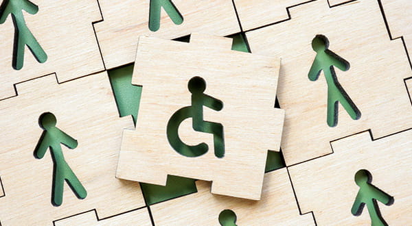 Invalidità civile |  Immagine di un puzzle con sopra l'icona di una carrozzina circondato da altri pezzi di puzzle con sopra l'icona di persone