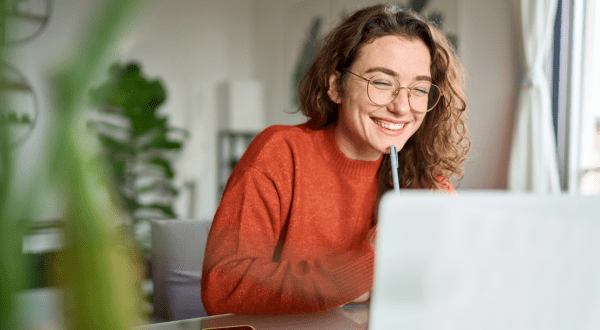 Lavori per studenti | Immagine di anteprima con studentessa sorridente mentre lavora da casa