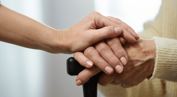 Legge 104 permessi lavoro | Immagine di anteprima dell'articolo con le mani in primo piano di un anziano e di un caregiver