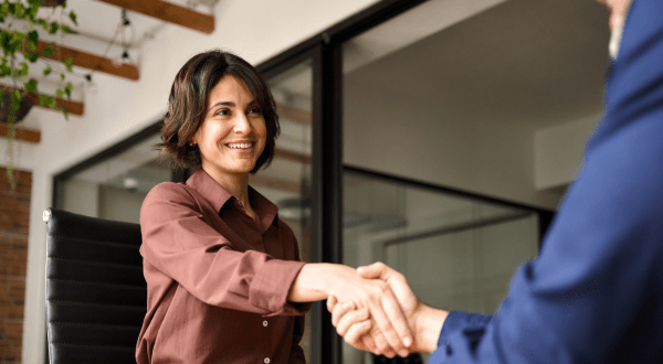 Onboarding aziendale | Immagine di una stretta di mano tra una donna neoassunta e HR Manager