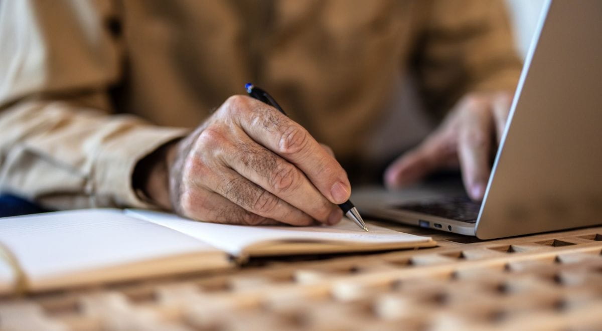 Pensione anticipata | Foto con dettaglio di mano anziano di uomo che scrive su un taccuino