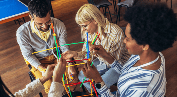 Team building | Immagine di anteprima dell'articolo con lavoratori e lavoratrici di età ed etnia diverse impegnati in un gioco di gruppo