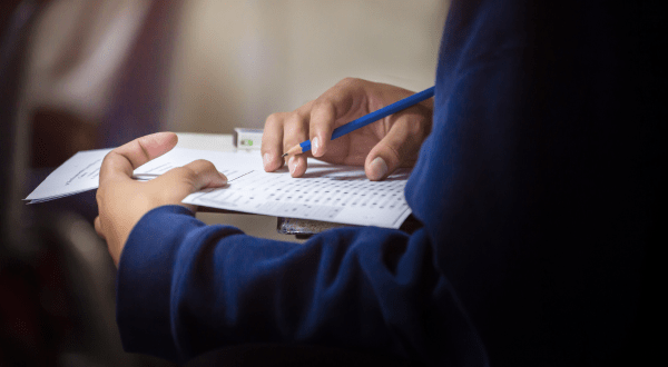Test attitudinali per il lavoro | Dettaglio della mano di una candidata mentre svolge il test