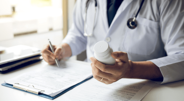 Orari visita fiscale | Immagine di anteprima con mani di un medico che prende appunti relativi a un farmaco