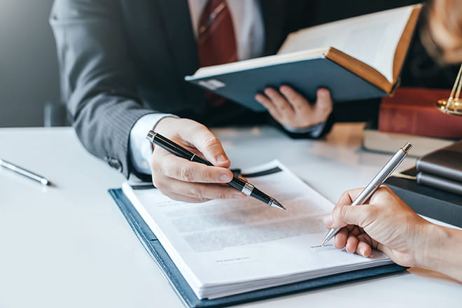 Legge di bilancio 2025 | Immagine di una persona che indica con la penna dove firmare il contratto ad un altra persona