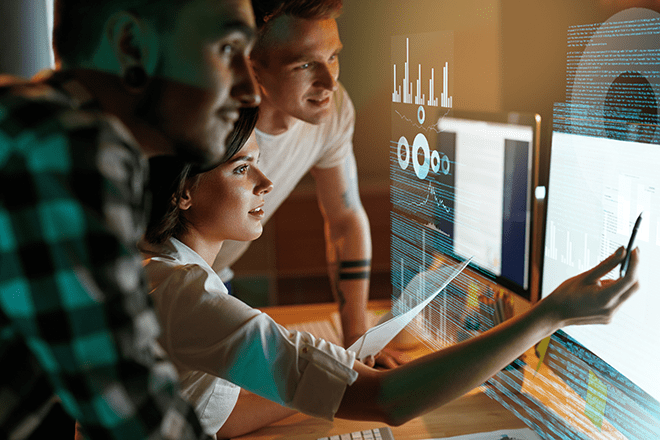 Professioni digitali più richieste | Immagine di tre persone che stanno lavorando al pc e indicano con una penna lo schermo.